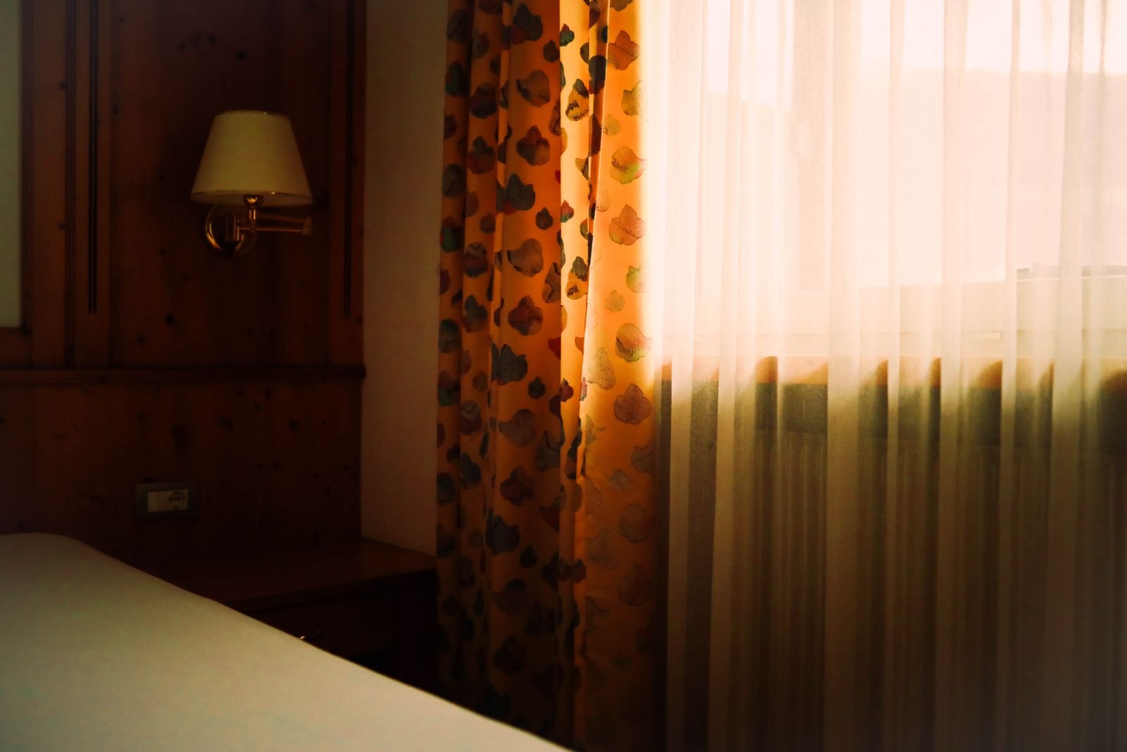 Sunlit bedroom with a bed, curtains and a large window