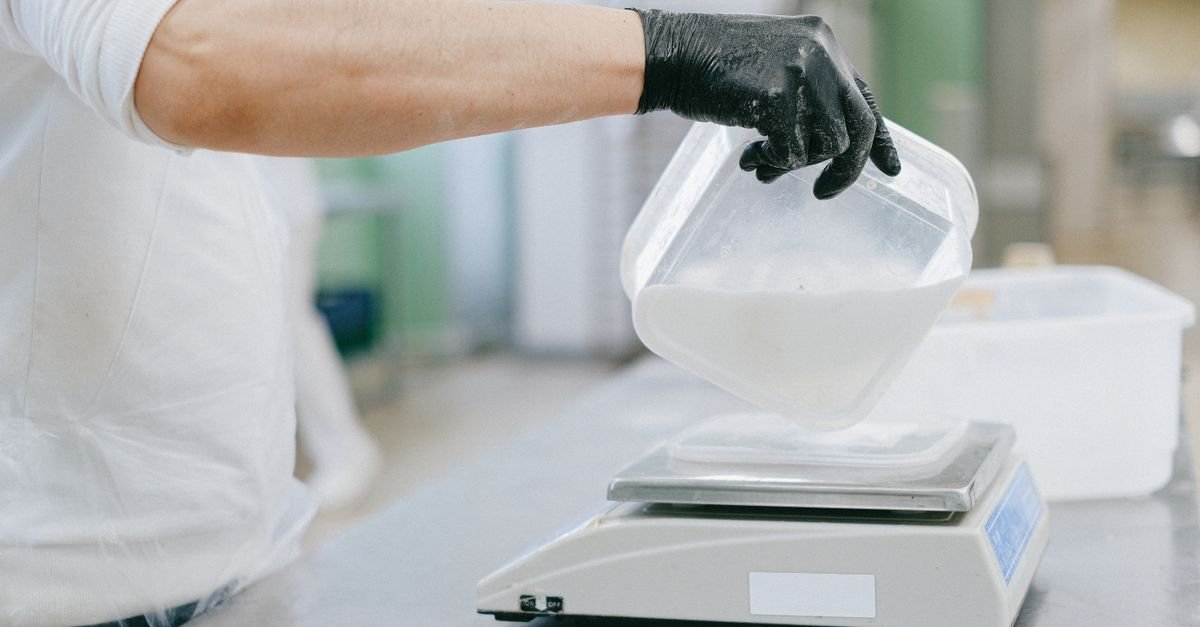 Person weighing an ingredient on a digital kitchen scale