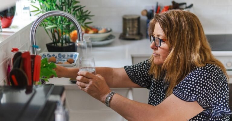 Woman filling a drinking glass at a kitchen sink