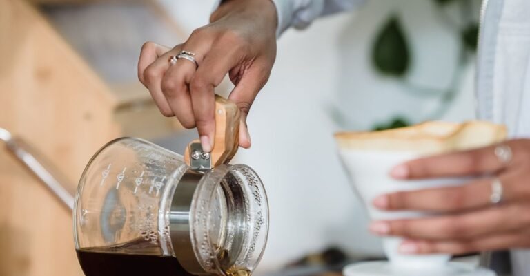 Coffee being poured from a glass carafe into a mug on a kitchen counter